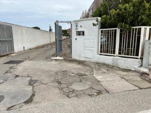 eine gekrackte Straße mit einem Tor und einem Zaun in der Unterkunft Calamaterdomini a 2 passi dal mare in Brindisi