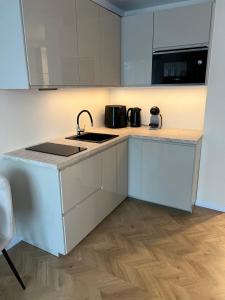 a white kitchen with a sink and a stove at AV apartamentai Palangoje in Palanga