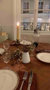 a wooden table with plates and glasses and a candle at Appartement de charme proche château et forêt in Fontainebleau