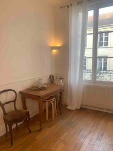 a room with a table and a chair and a window at Appartement de charme proche château et forêt in Fontainebleau