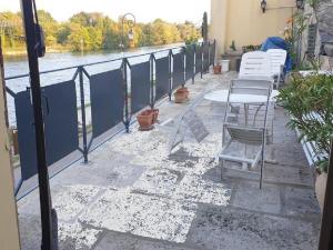 eine Terrasse mit Stühlen und Tischen sowie Flussblick in der Unterkunft Grand 2P Terrasse bord de seine in Mantes-la-Jolie