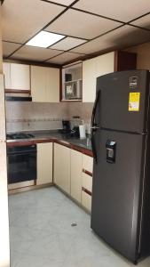eine Küche mit einem schwarzen Kühlschrank im Zimmer in der Unterkunft Lindo apto al lado del parque del ingenio in Cali