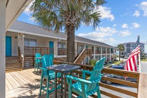 a table and chairs on a deck with a palm tree at The Beach House at Oak Island by Carolina Resorts in Oak Island