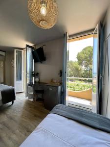 Schlafzimmer mit einem Bett, einem Schreibtisch und einem Fenster in der Unterkunft Hotel La Calanque in Mandelieu-la-Napoule