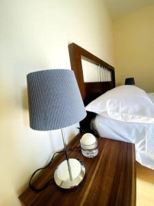 a lamp on a wooden table next to a bed at Private Gated Studio Flat in Buckinghamshire