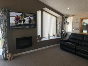 a living room with a couch and a flat screen tv at Hot Tub Accommodation North Wales Lodge in Rhyl