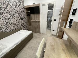 um pequeno quarto com uma cama e uma televisão em Hotel Altinate em Lido di Jesolo