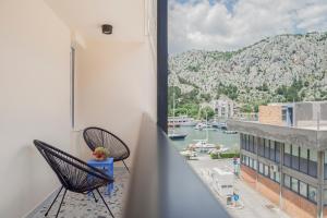 a balcony with two chairs and a view of a harbor at Apartment Vito in Omiš