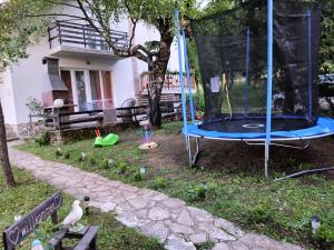 a playground with a trampoline in front of a house at Holiday home Ivano in Korenica