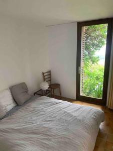 ein Schlafzimmer mit einem Bett und einem großen Fenster in der Unterkunft Maison Gaou Benat, magnifique vue mer in Bormes-les-Mimosas