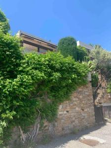 eine Backsteinmauer mit Büschen darüber in der Unterkunft Maison Gaou Benat, magnifique vue mer in Bormes-les-Mimosas