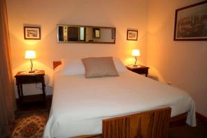 1 dormitorio con 1 cama blanca grande y 2 lámparas en Casa Velha do Fumeiro, en Santa Eulália