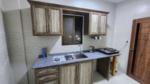 uma cozinha com um lavatório e armários de madeira em Montreal apartment Shobak near petra em Nijil