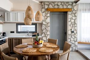 a kitchen and dining room with a wooden table and chairs at Lithos Luxury Villa in Archangelos