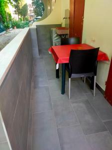 un tavolo rosso e sedie su un pavimento piastrellato di BILOCALE Villa Lara a Cesenatico
