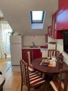 eine Küche mit einem Tisch und Stühlen sowie eine Küche mit roten Schränken in der Unterkunft JANA in Veliko Gradište