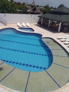 a large blue swimming pool with chairs and a pavilion at CABAÑA MANANTIAL DE DIOS in Turbo