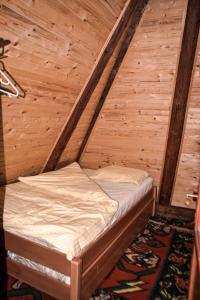 a small bed in a room with wooden walls at Na krovu svijeta in Lukomir