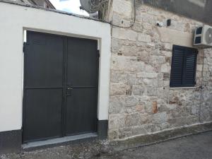 een zwarte deur aan de zijkant van een bakstenen gebouw bij GrannyAnny in Šibenik