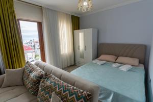 a bedroom with a bed and a couch and a window at Flora Trabzon Apart in Pelitli