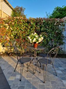 einen Tisch mit zwei Stühlen und eine Vase mit Blumen in der Unterkunft Chambre au calme proche de la nature in Auxi-le-Château