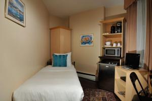 a small room with a bed and a microwave at Victoria's Mansion Guest House in Toronto