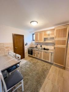 uma cozinha com armários de madeira e uma mesa e cadeiras em Apartments & Rooms Brijest em Plav