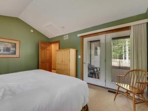 um quarto com uma cama, uma janela e uma cadeira em 658 Disciples Village Condo em Boyne Falls