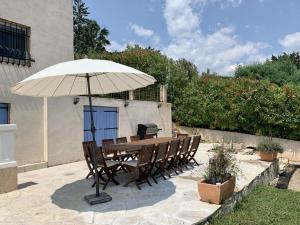 una mesa y sillas con una sombrilla en el patio en Villa des Sapins en Peymeinade