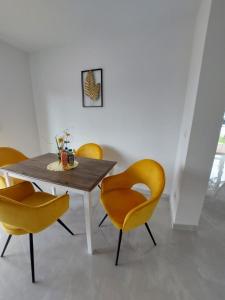 a dining room with a wooden table and yellow chairs at Fancy Blue Moderne Wohnung mit sehr großem Garten in Gerasdorf bei Wien