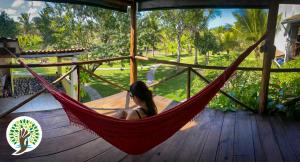 een vrouw in een hangmat op een veranda bij Fazenda Eco-Jardim in Una