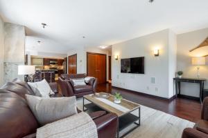 a living room with leather furniture and a tv at Greyhawk 123 by Outpost Whistler in Whistler