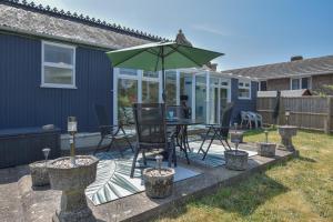 a patio with a table and a green umbrella at Siesta a spacious family home from home in Ryde