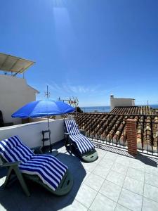 2 Liegestühle und ein Sonnenschirm auf dem Balkon in der Unterkunft Casa MIJAS PUEBLO La Villa Nueva in Mijas