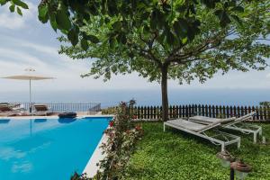 a swimming pool with a tree and an umbrella at Carmel Villas in Drymon