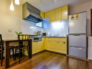 a kitchen with yellow cabinets and a table and a refrigerator at Enishi - Vacation STAY 10139v in Otaru