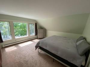 ein Schlafzimmer mit einem großen Bett und zwei Fenstern in der Unterkunft Fabulous Waterfront Home Midcoast Maine 