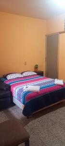 a bedroom with a bed with a colorful blanket at Hotel Maya America in Panajachel