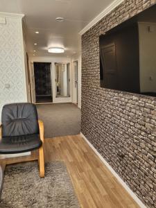 a room with a brick wall with a chair and a television at lägenhet i Borgholms villa in Borgholm