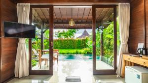 a living room with a television and a pool at Uma Kakul Villas in Tegalalang