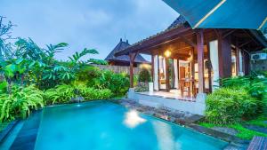 a villa with a swimming pool in front of a house at Uma Kakul Villas in Tegalalang