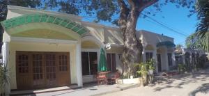 a white house with an umbrella and a tree at Lucky Garden Inn in Puerto Princesa City