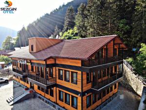 a large wooden house with a brown roof at Sezgin Hotel in Uzungol