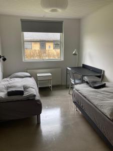 a bedroom with two beds and a desk and a window at Villa med private værelser delt badeværelse/køkken, viby sj. in Viby