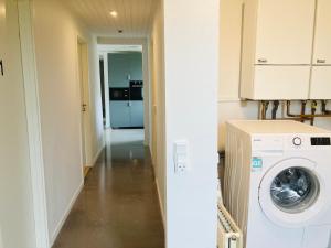 een wasruimte met een wasmachine en een hal bij Villa med private værelser delt badeværelse/køkken, viby sj. in Viby