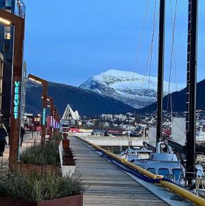 muelle con barcos en un puerto deportivo con una montaña cubierta de nieve en Vervet apartment, en Tromsø