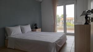 1 dormitorio con cama blanca y ventana grande en Villa Dimitrios(2 independent apartments 200sq m), en Vourvourou