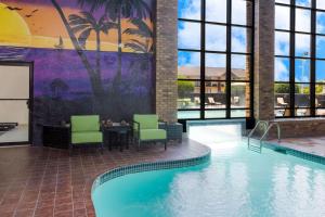 een zwembad met stoelen en een tafel in de lobby van het hotel bij SureStay Plus Hotel by Best Western Greenwood in Greenwood