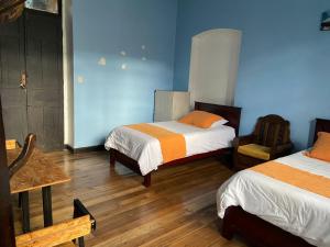 Habitación con 2 camas, paredes azules y suelo de madera. en Villa Bonita Hostel en Riobamba