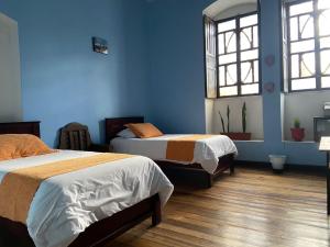 2 camas en una habitación con paredes y ventanas azules en Villa Bonita Hostel, en Riobamba